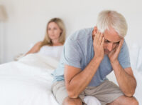 Older man sitting sadly on the edge of the bed