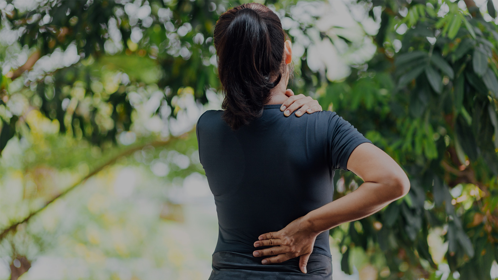 woman outside holding her back