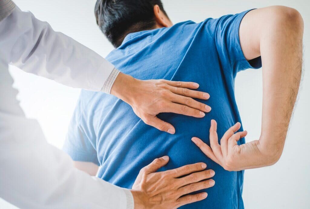 man showing where his back pain is