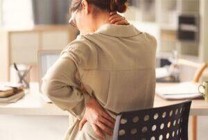 woman suffering from back pain while trying to work